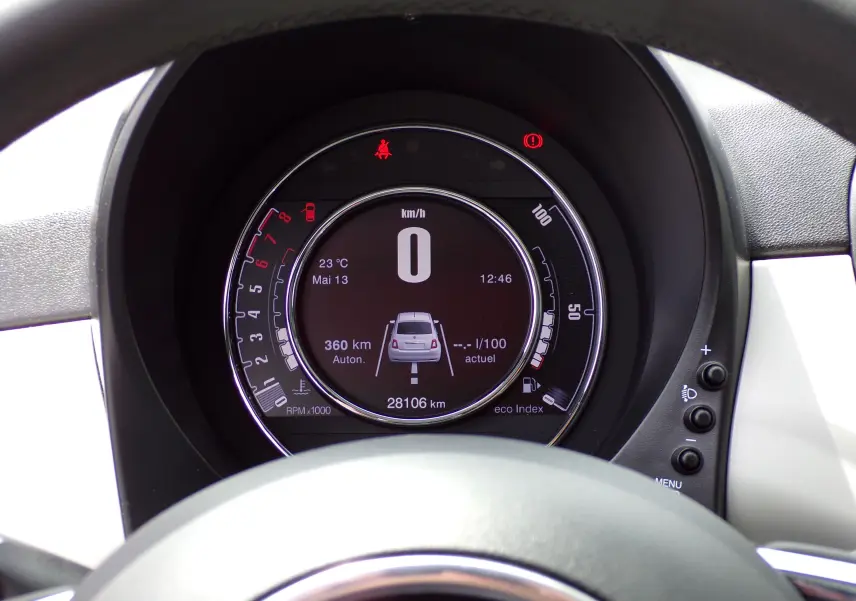 Vue rapprochée du tableau de bord numérique de la Fiat 500 blanc 2019, affichant vitesse et autonomie.