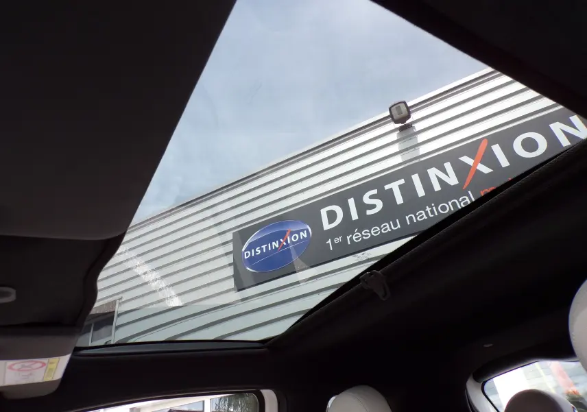 Vue intérieure du toit ouvrant panoramique d'une Fiat 500 blanche de 2019 avec sièges en cuir blanc et tissu noir.