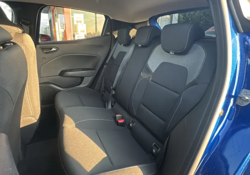 Vue intérieure arrière droite de la Renault Clio 2025 bleu iron, montrant les sièges arrière en tissu noir avec surpiqûres blanches.