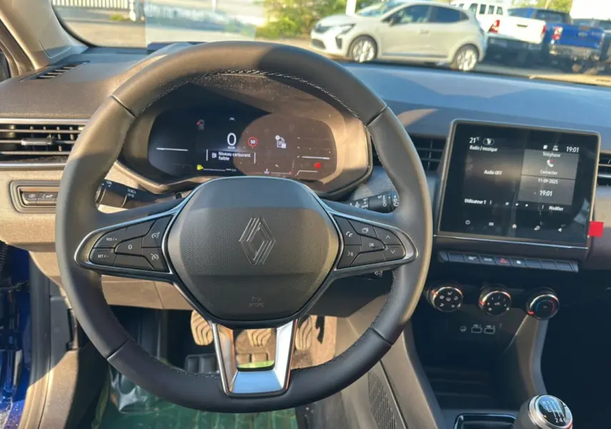 Vue intérieure centrée sur le volant de la Renault Clio DCI 100 Evolution Camera 2025, avec tableau de bord digital et écran tactile.