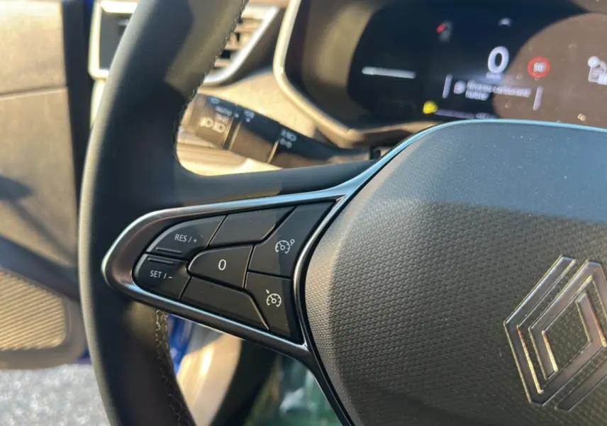 Gros plan sur le volant de la Renault Clio DCI 100 Evolution Camera 2025 bleu iron, avec commandes de régulateur de vitesse.