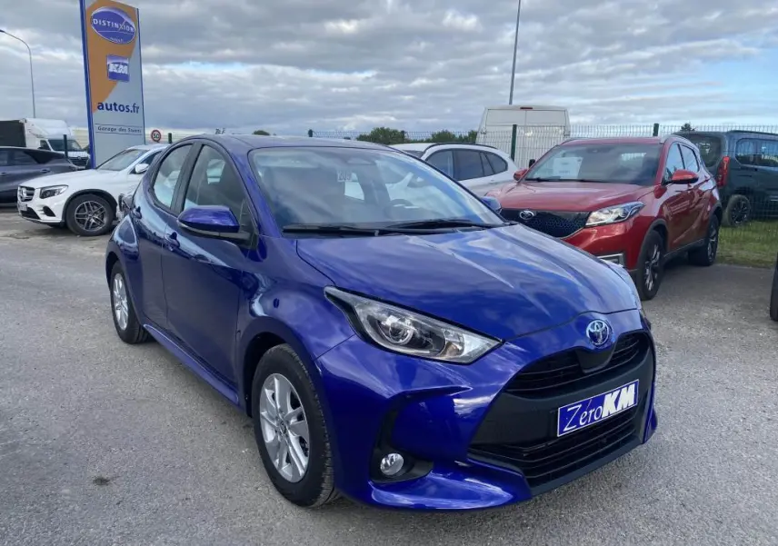 Toyota Yaris hybride 2025 bleu Genièvre vue 3/4 avant avec jantes alliage 15 pouces et calandre noire distinctive.