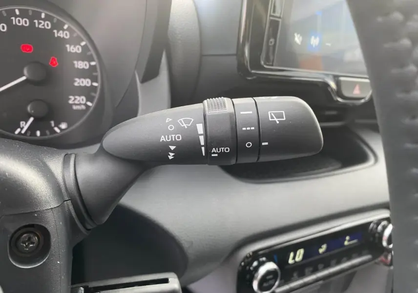 Gros plan sur la commande d'essuie-glace à gauche du volant dans l'habitacle d'une Toyota Yaris hybride 2025.