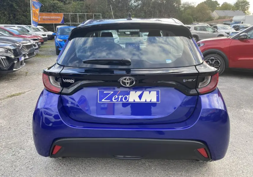 Vue arrière d'une Toyota Yaris hybride 2025 en bleu Genièvre avec toit noir et feux arrière distinctifs.
