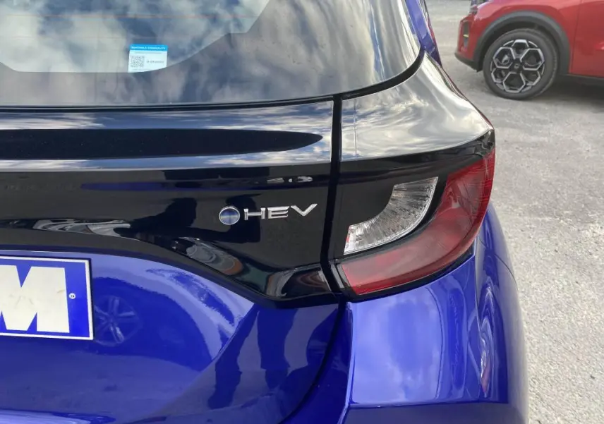 Gros plan sur le feu arrière droit et le logo HEV d'une Toyota Yaris hybride 2025 en bleu Genièvre.