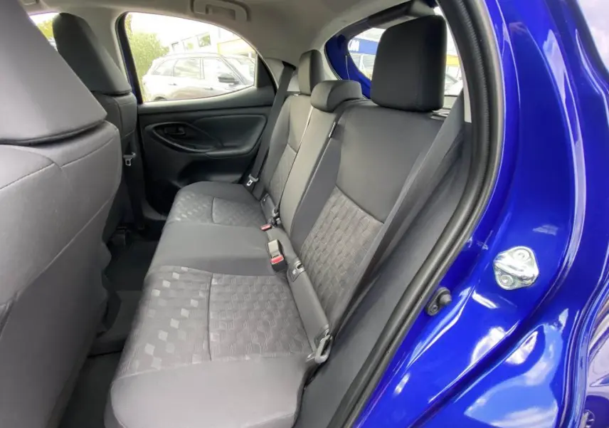 Vue intérieure côté droit sur la banquette arrière noire d'une Toyota Yaris 2025 bleu Genièvre avec porte ouverte.
