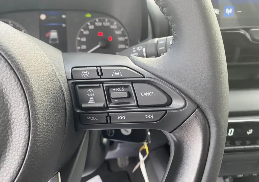 Gros plan sur les commandes au volant à droite de la Toyota Yaris 2025, avec tableau de bord et écran tactile en arrière-plan.