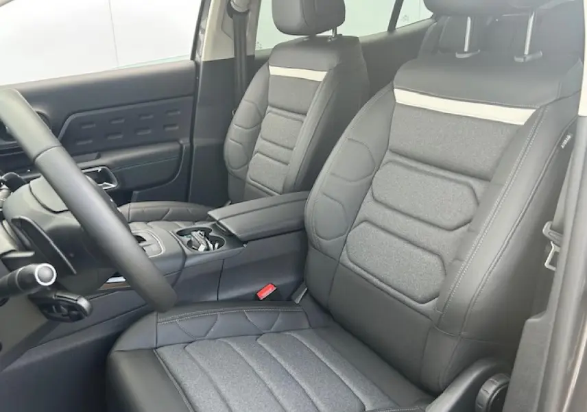 Vue intérieure côté gauche montrant les sièges avant gris anthracite avec accoudoir central et volant partiel du Citroën C5 Aircross.