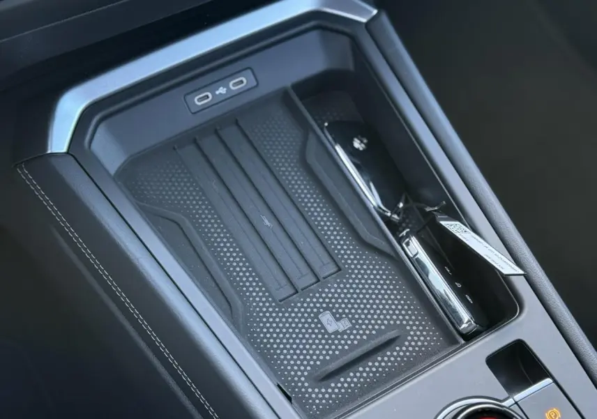 Gros plan sur la console centrale noire du Volkswagen T-Roc 2026 avec zone de recharge sans fil et ports USB-C.