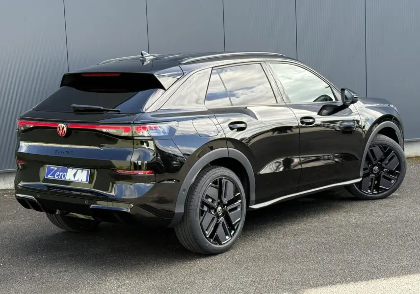 Vue 3/4 arrière droite du Volkswagen T-Roc noir Ébène avec jantes noires sport et hayon électrique visible.