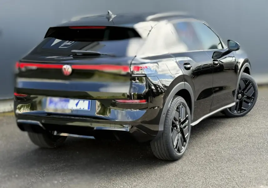 Volkswagen T-Roc noir ébène en 3/4 arrière droit, avec jantes noires et bandeau lumineux arrière distinctif.