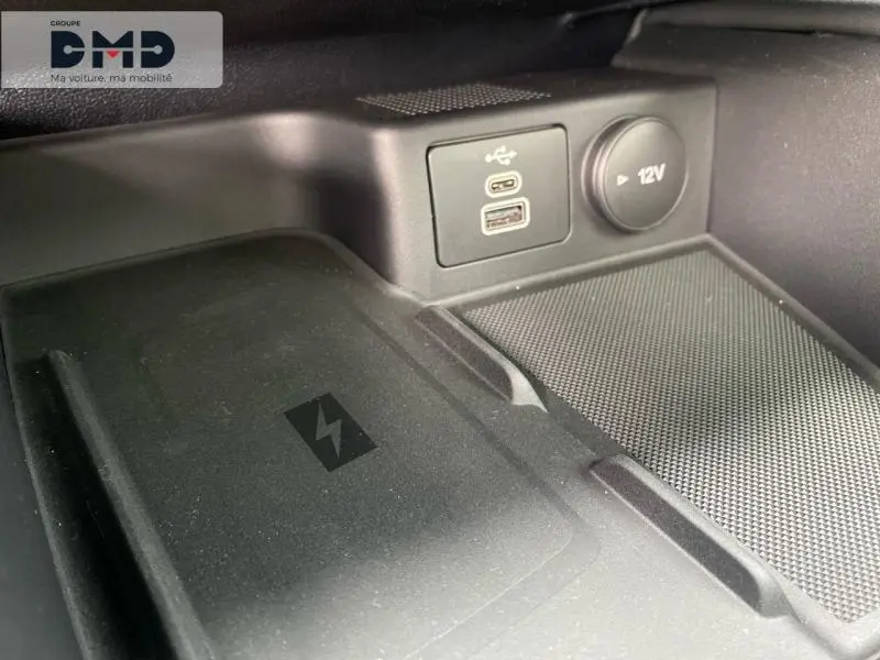 Gros plan sur la console centrale du Ford Kuga 2026, montrant prise USB, prise 12V et chargeur sans fil noir.