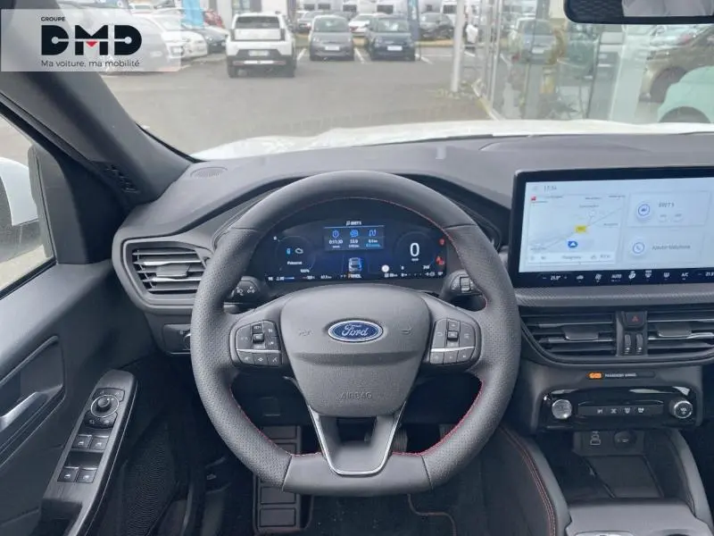 Vue intérieure centrée sur le volant Ford Kuga blanc Glacier, tableau de bord numérique et écran tactile GPS visible.