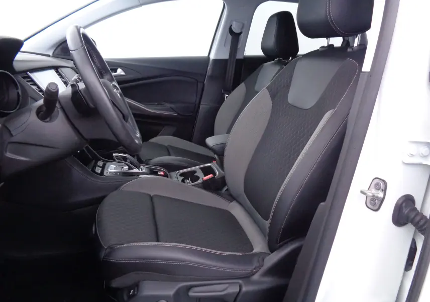 Intérieur côté conducteur de l'Opel Grandland X blanc perle, sièges bi-matière noirs et gris avec coutures apparentes.