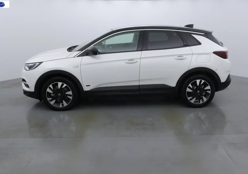 Profil côté gauche d'un Opel Grandland X blanc perle métal avec toit noir et jantes bicolores.