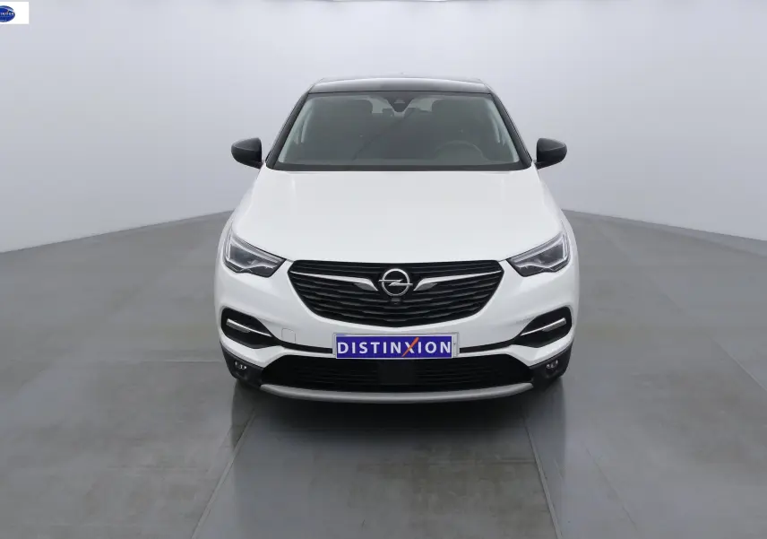 Vue frontale d'un Opel Grandland X blanc perle métal avec calandre noire et toit panoramique sombre.
