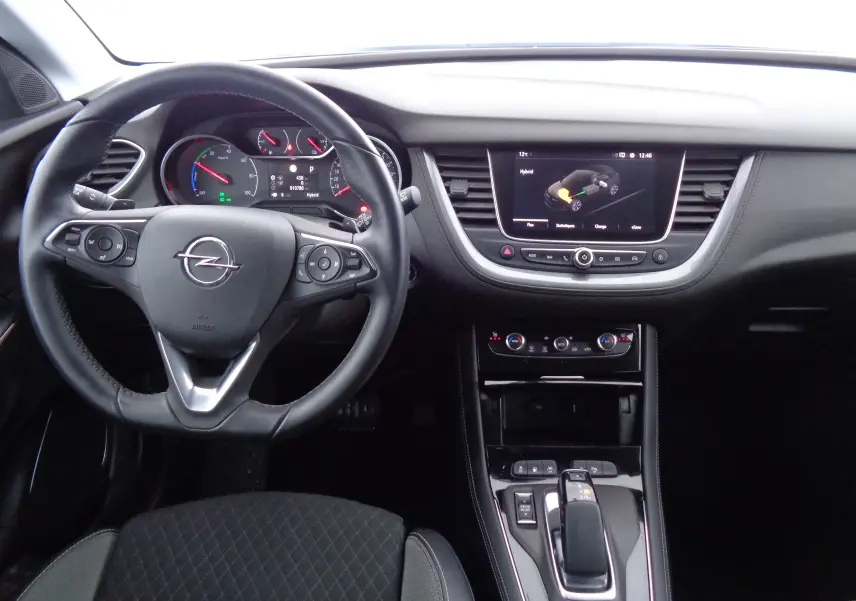 Vue intérieure avant de l'Opel Grandland X hybride, tableau de bord noir avec écran tactile et volant multifonction.