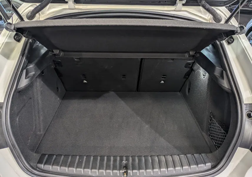 Coffre ouvert vu de l'arrière d'une BMW Série 1 F40 blanche, montrant un espace de chargement propre et spacieux.