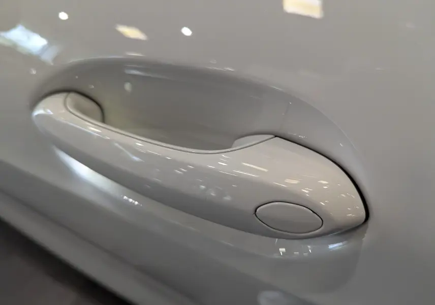 Poignée de porte blanche alpin en gros plan sur une BMW Série 1 F40 18d 2023 finition M Sport.