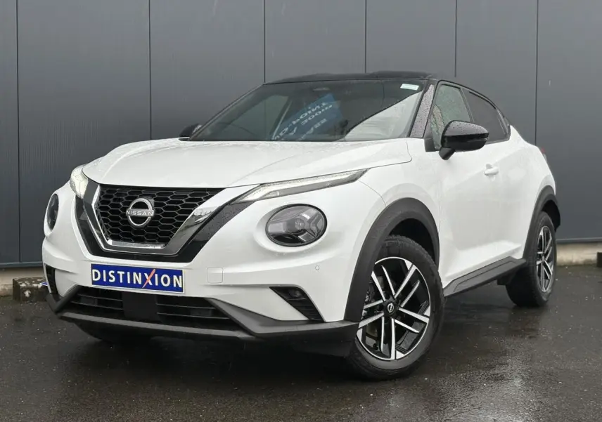 Nissan Juke blanc nacré en 3/4 avant droit, avec toit noir et jantes alliage 17 pouces au design moderne.