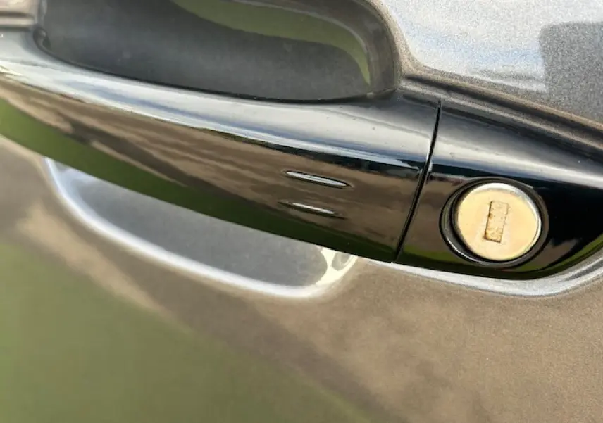 Poignée de porte noire brillante avec serrure sur la portière gris platinium métallisé d'une Citroën C5 Aircross 2025.
