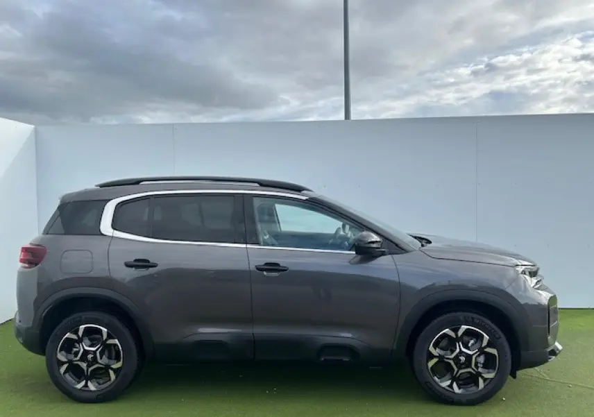 Profil droit du Citroën C5 Aircross gris platinium métallisé avec jantes alliage bi-ton et barres de toit noires.