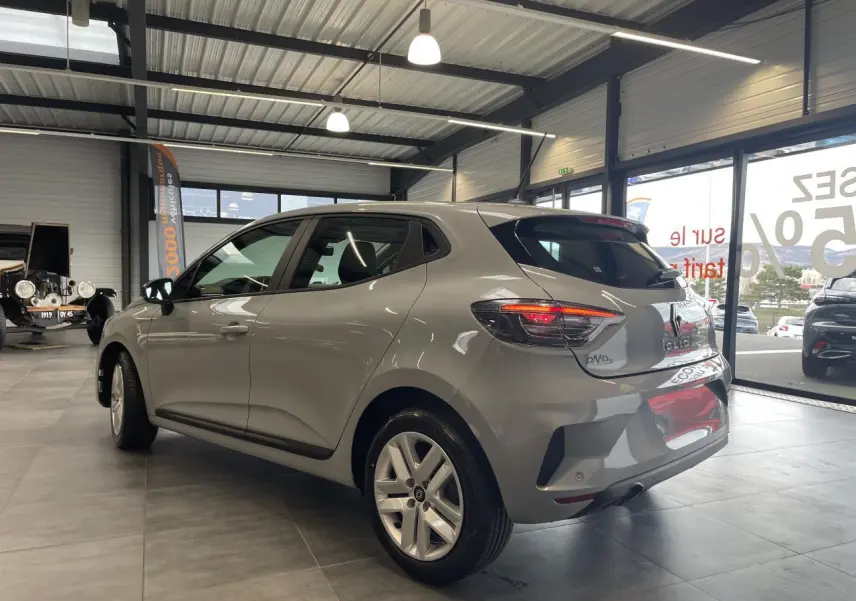 Renault Clio 2025 gris Rafale vue 3/4 arrière droit en intérieur, feux arrière LED allumés et jantes alliage.