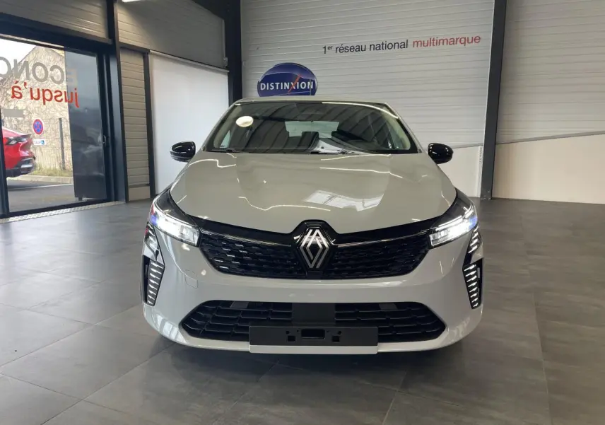 Vue de face d'une Renault Clio 1.5 Blue dCi 2025 gris Rafale avec calandre noire et feux LED allumés.