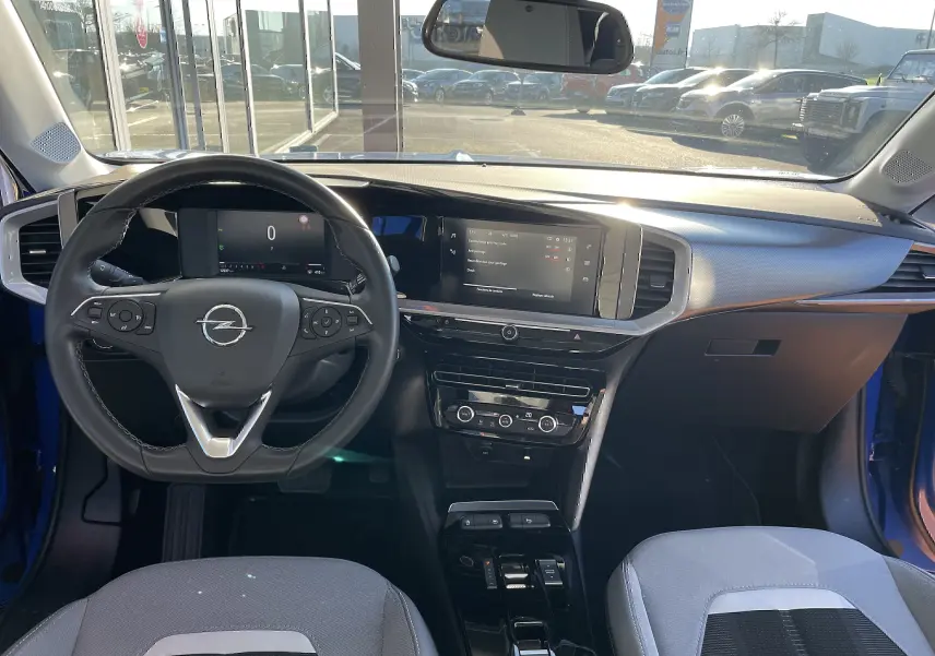 Intérieur de l'Opel Mokka 2023 en bleu Voltak, vue depuis le siège conducteur sur le tableau de bord et volant multifonction.