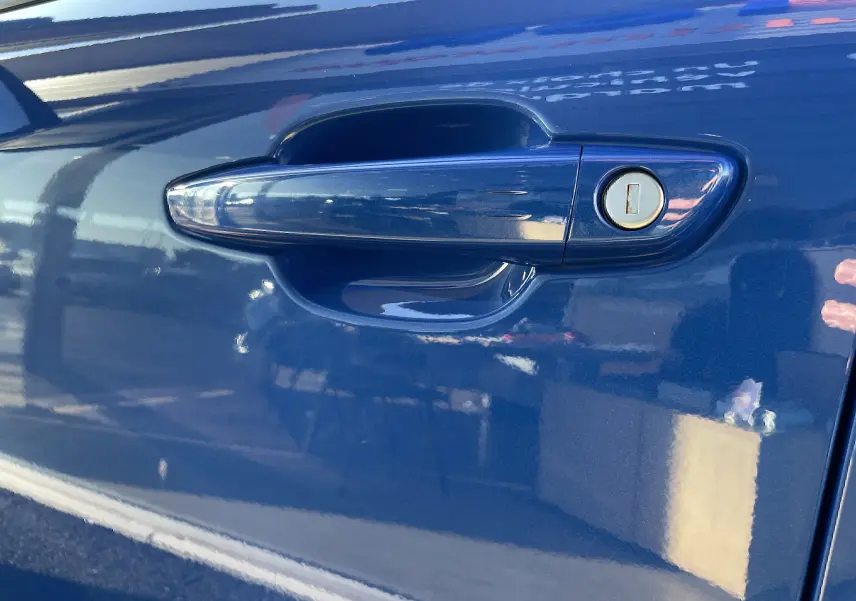 Poignée de porte côté gauche en gros plan sur Opel Mokka 2023 bleu Voltak avec serrure intégrée.