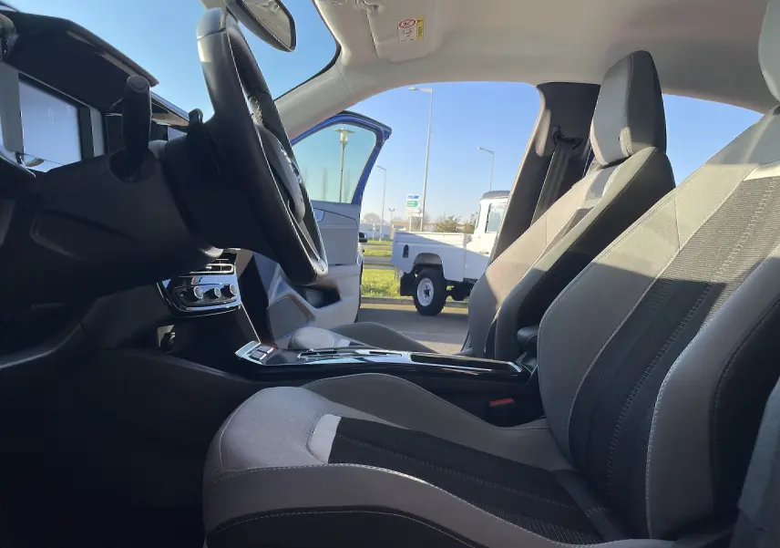 Vue intérieure côté conducteur de l'Opel Mokka 2023, sièges gris noir et volant multifonction avec tableau de bord moderne.