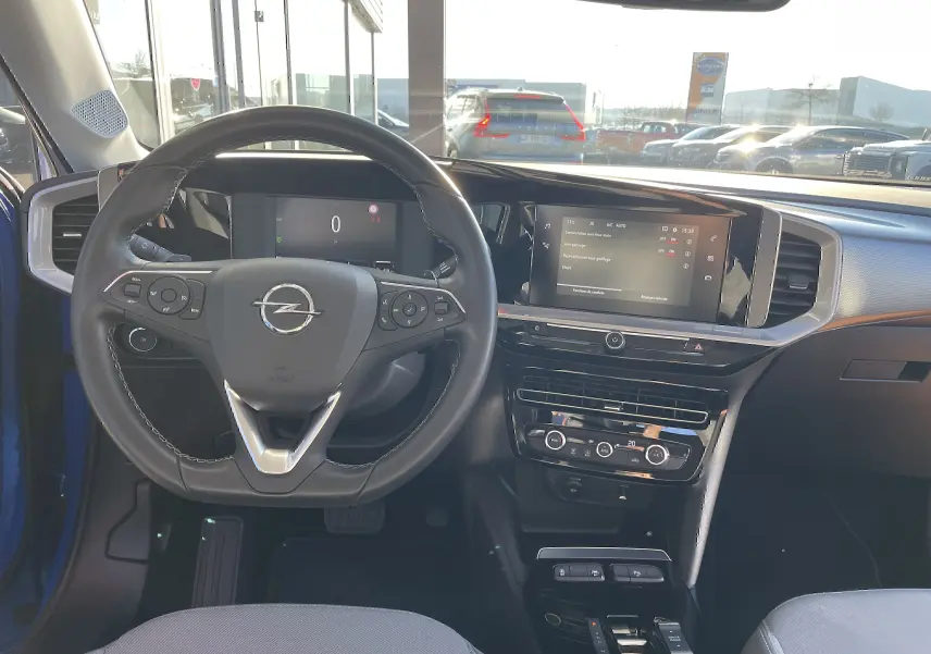 Vue intérieure de l'Opel Mokka bleu voltak 2023, tableau de bord moderne avec écran tactile et volant multifonction.