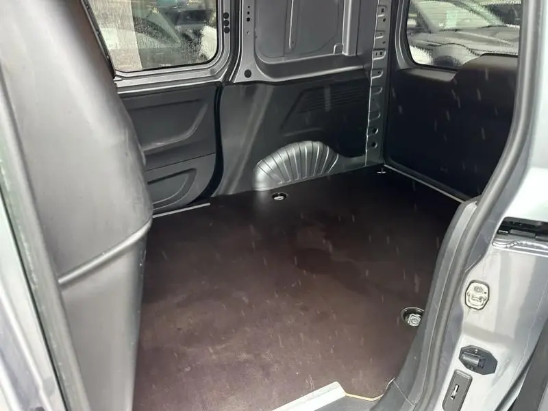 Vue intérieure côté droit du coffre vide du Citroën Berlingo van gris métal, montrant le plancher et les parois métalliques.