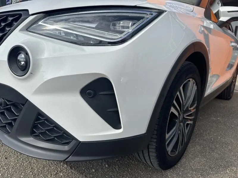 Gros plan sur l'avant droit blanc Nevada Métal du SEAT Arona 2022, mettant en valeur le phare LED et la jante alu 17 pouces.