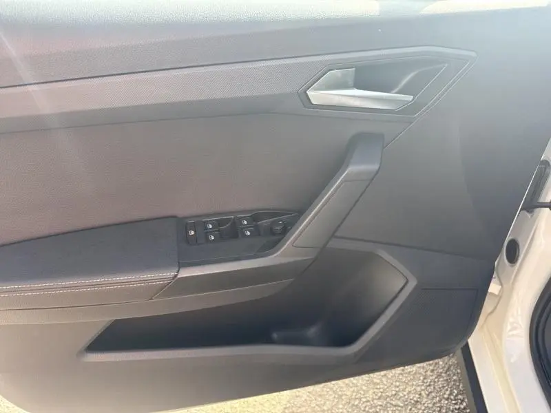 Intérieur de la porte avant gauche de la SEAT Arona blanc Nevada, avec commandes électriques et poignée argentée.