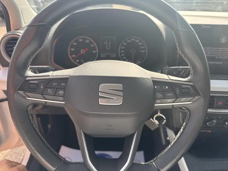 Volant cuir multifonction noir avec logo SEAT au centre, tableau de bord et commandes visibles dans un SEAT Arona 2022.