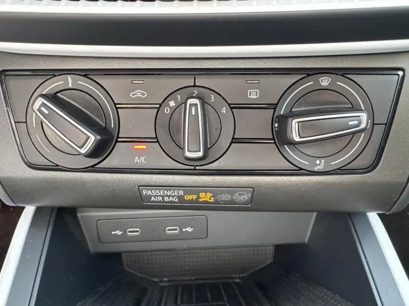 Gros plan sur les commandes de climatisation noires du SEAT Arona blanc Nevada Métal avec indication d'airbag passager désactivé.