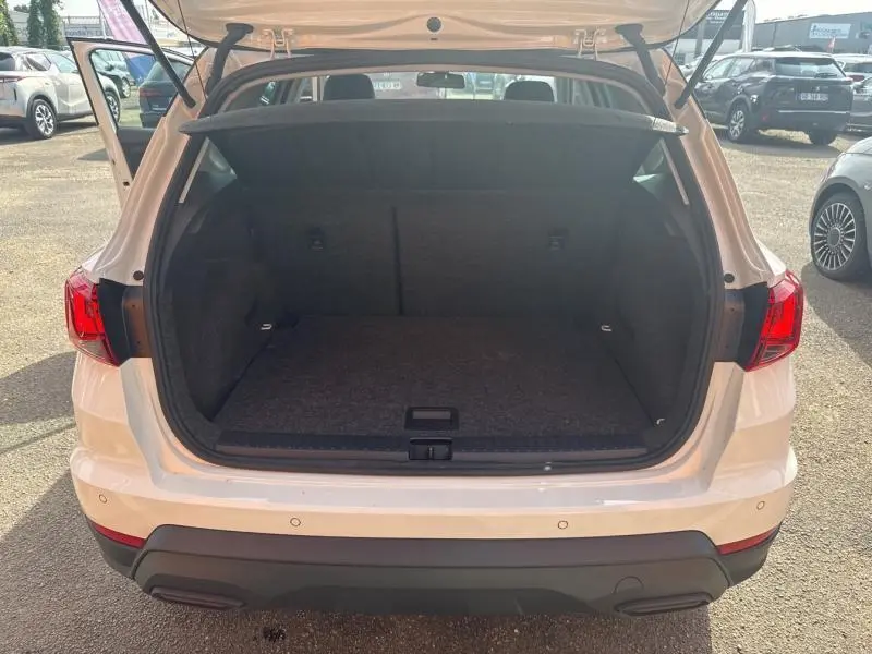 Coffre ouvert vu de l'arrière d'un SEAT Arona blanc Nevada avec feux arrière LED et pare-chocs noir.