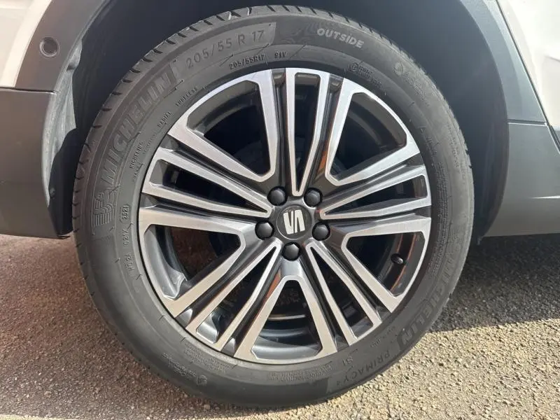 Gros plan sur la jante alu 17 pouces gris et noir du côté avant droit d'un SEAT Arona blanc Nevada Métal.