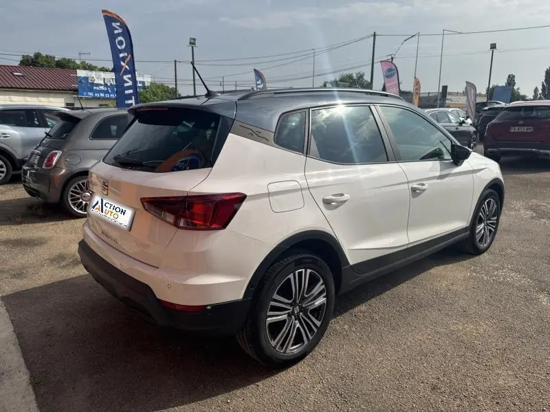 Vue 3/4 arrière droite d'un SEAT Arona blanc Nevada métal avec toit gris magnétique et jantes alu 17 pouces.