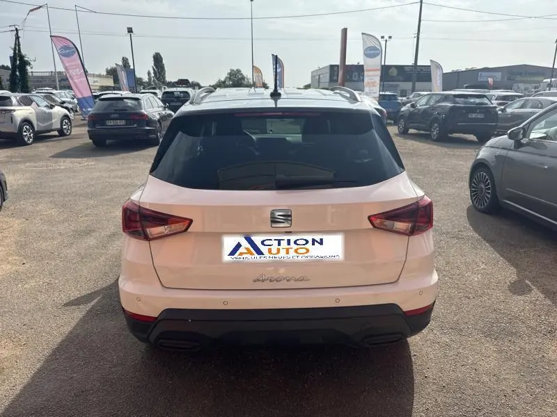 Vue arrière d'une SEAT Arona blanc Nevada avec toit gris magnétique, feux arrière LED et barres de toit visibles.