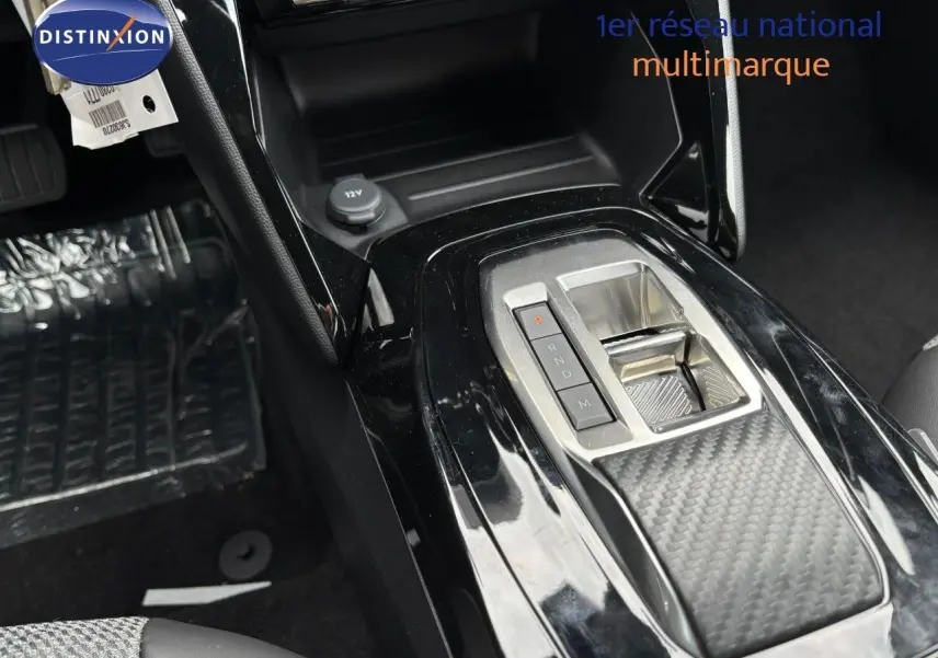 Gros plan sur la console centrale noire brillante du Peugeot 2008 Hybrid 2025 avec levier de vitesses électronique.