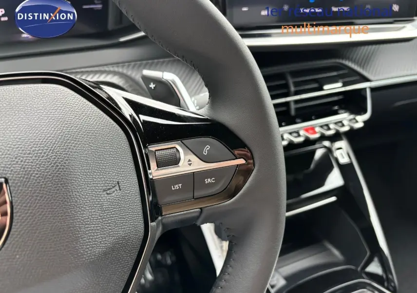Gros plan sur le volant en cuir noir et les commandes multimédia du Peugeot 2008 Hybrid 136ch Allure, intérieur moderne.