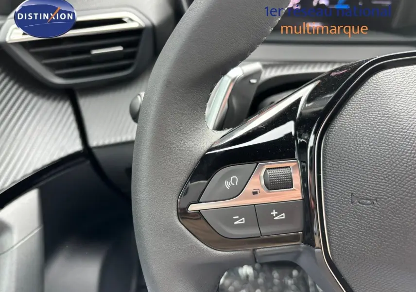 Gros plan sur le volant cuir noir du Peugeot 2008 Hybrid 136ch Allure, mettant en valeur les commandes intégrées côté gauche.