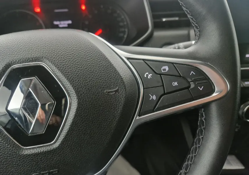 Gros plan sur le volant en cuir noir de la Renault Clio V 1.0 TCE 90 Zen avec commandes multifonctions côté droit.