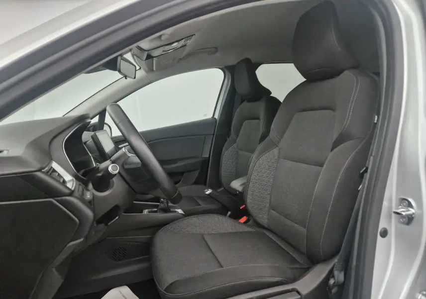 Vue intérieure côté conducteur de la Renault Clio V gris platine, sièges tissu noir avec motifs géométriques.