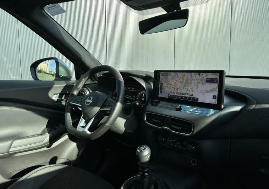 Intérieur du Nissan Juke 2025 noir, vue côté conducteur, tableau de bord avec écran tactile et volant cuir multifonction.