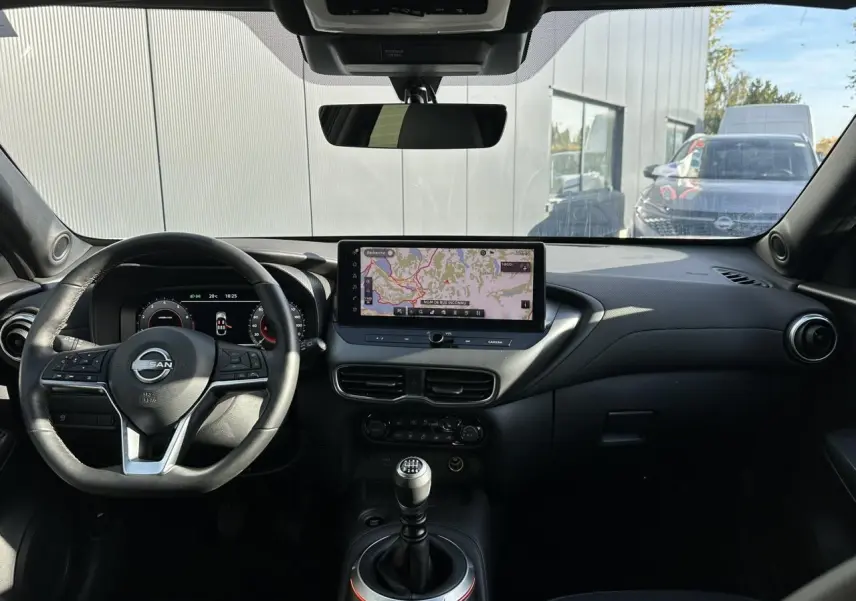Intérieur noir du Nissan Juke 2025 vu de face, avec tableau de bord digital et écran tactile central affichant la navigation.