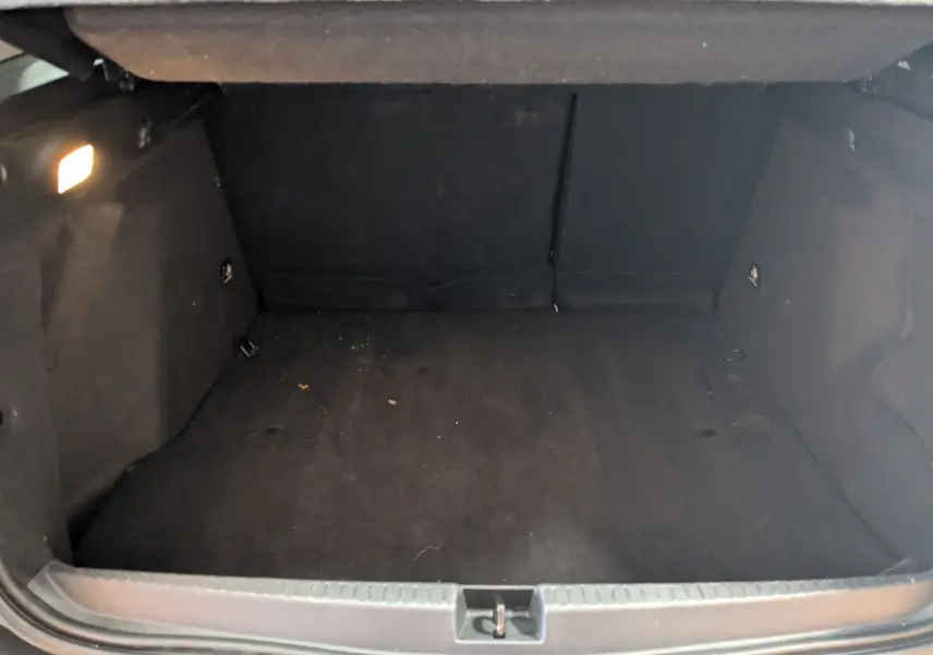 Coffre ouvert du Dacia Duster gris 2023, vue intérieure montrant l'espace de chargement vide et les parois en tissu noir.