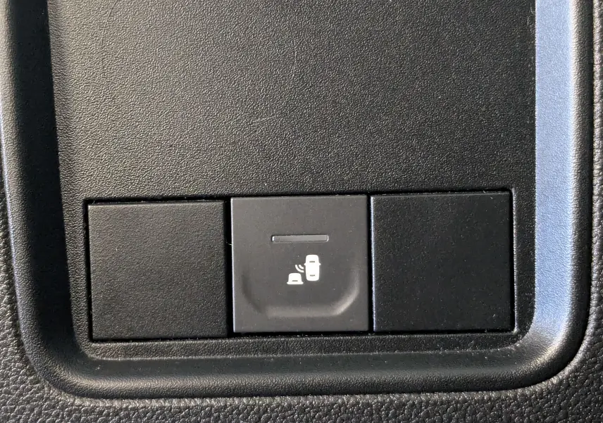 Gros plan sur le bouton d'alerte de détection d'angle mort dans l'habitacle du Dacia Duster gris 2023.